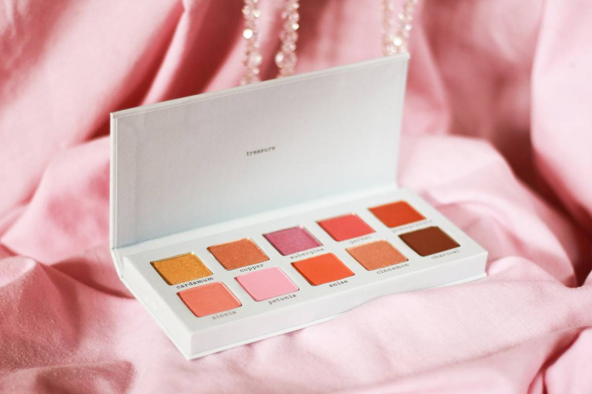 A compact subtle beauty palette with neutral eyeshadows, cream blush, and tinted balm arranged on a marble surface