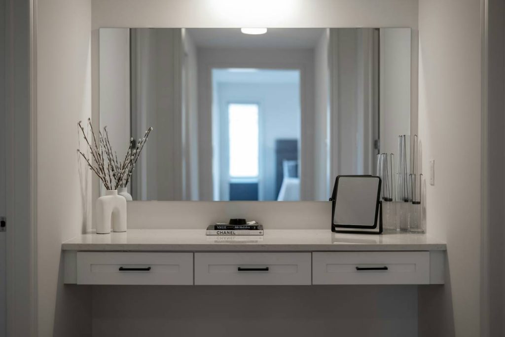 A modern vanity table with a large mirror and decor
