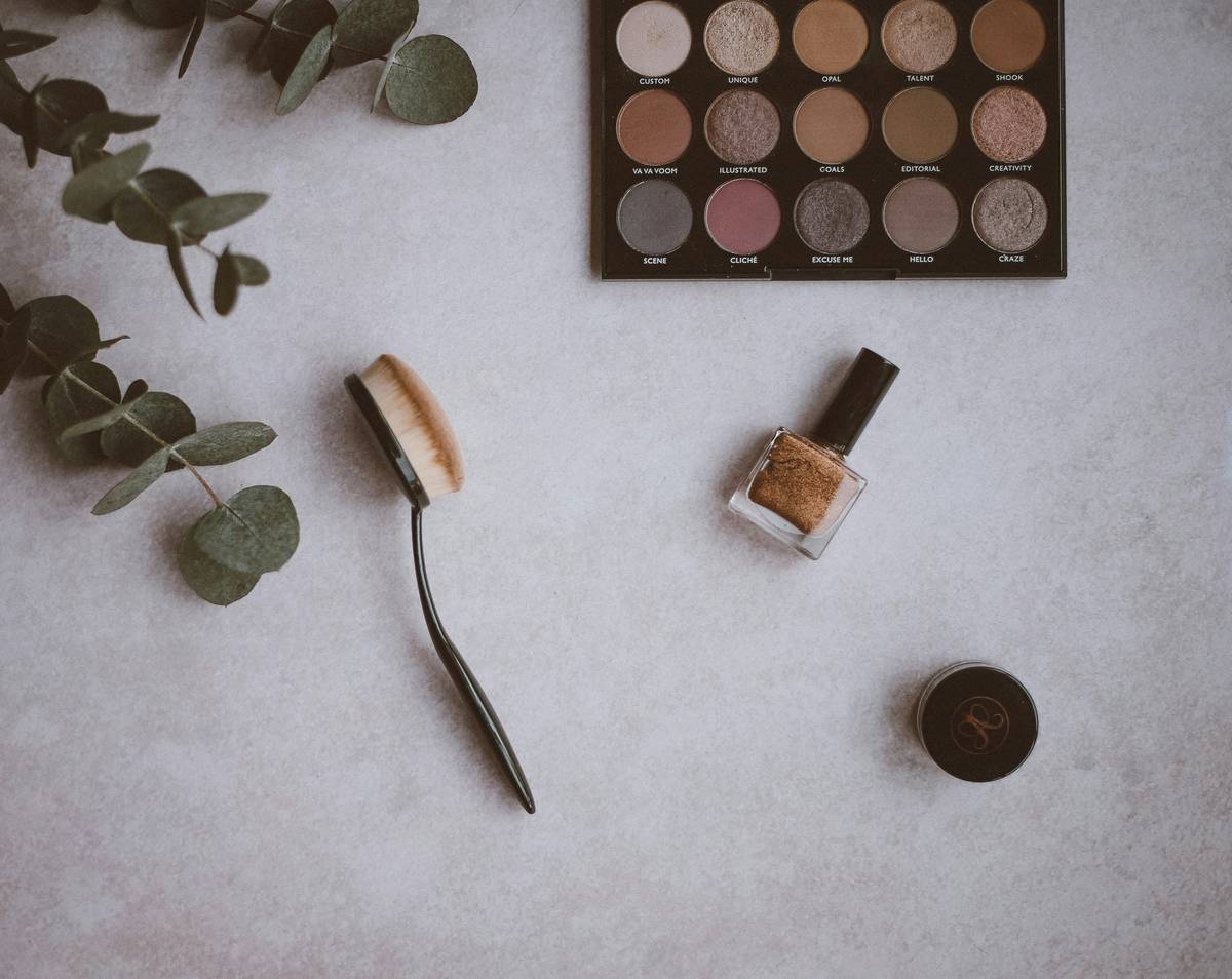 A curated soft makeup kit with nude lip balm, cream blush, and sheer foundation on a marble surface